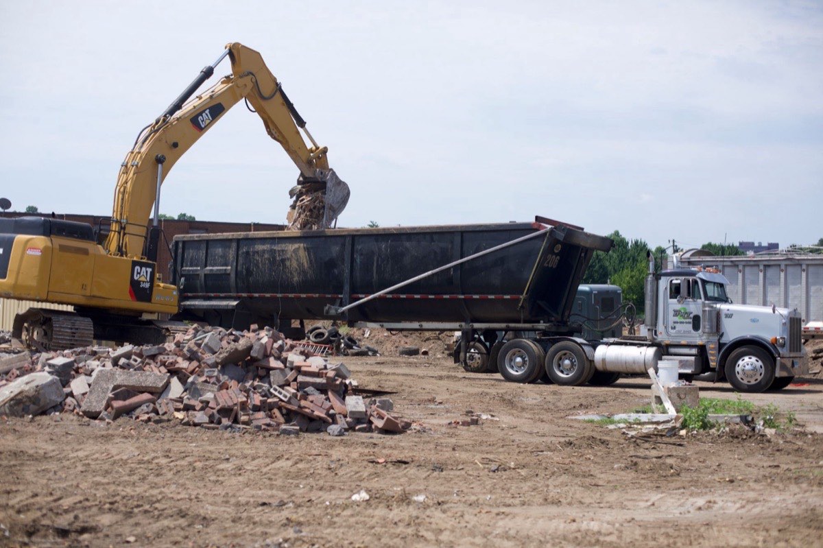 An excavator loading brick and concrete into a DWT trailer on a demolition site