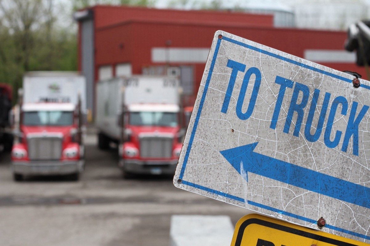 A &lsquo;to truck&rsquo; sign in the yard, with two tractors behind it